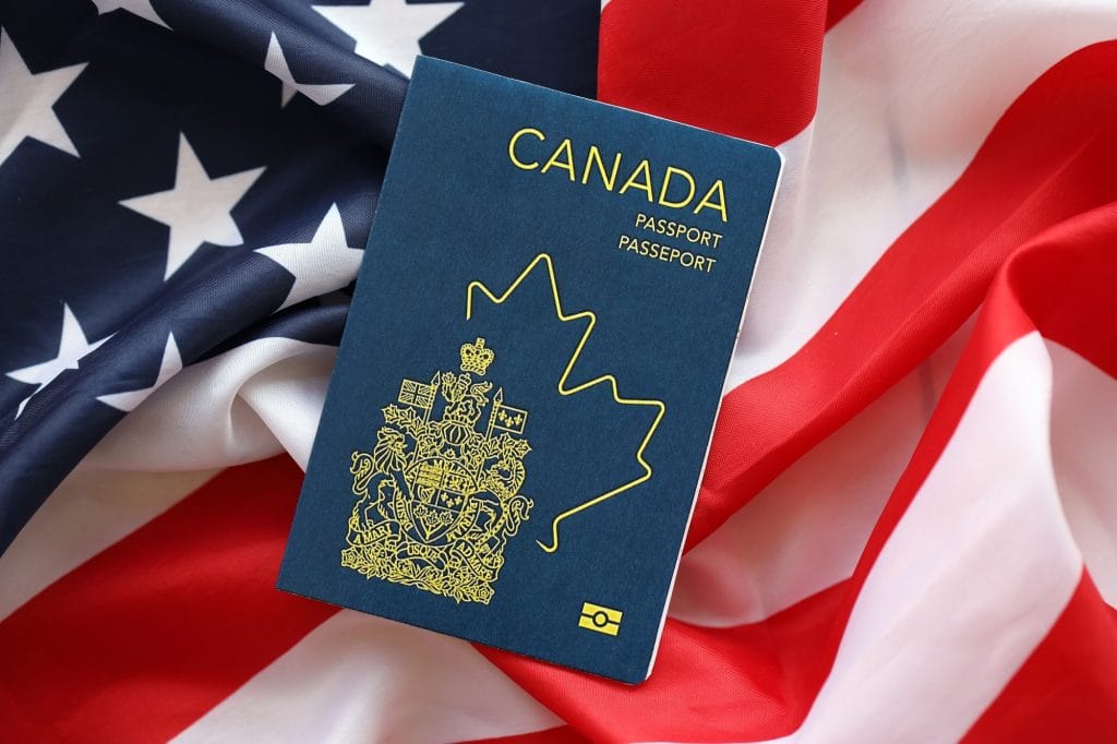 Canadian passport on United States national flag background close up. Tourism and diplomacy