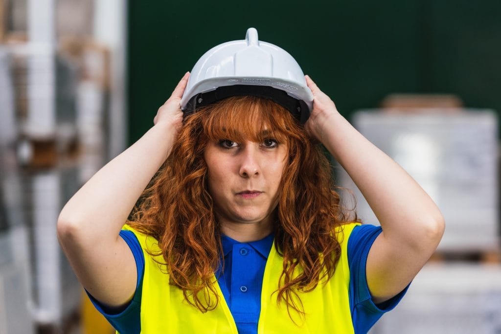 Female industrial worker putting on a hard helmet