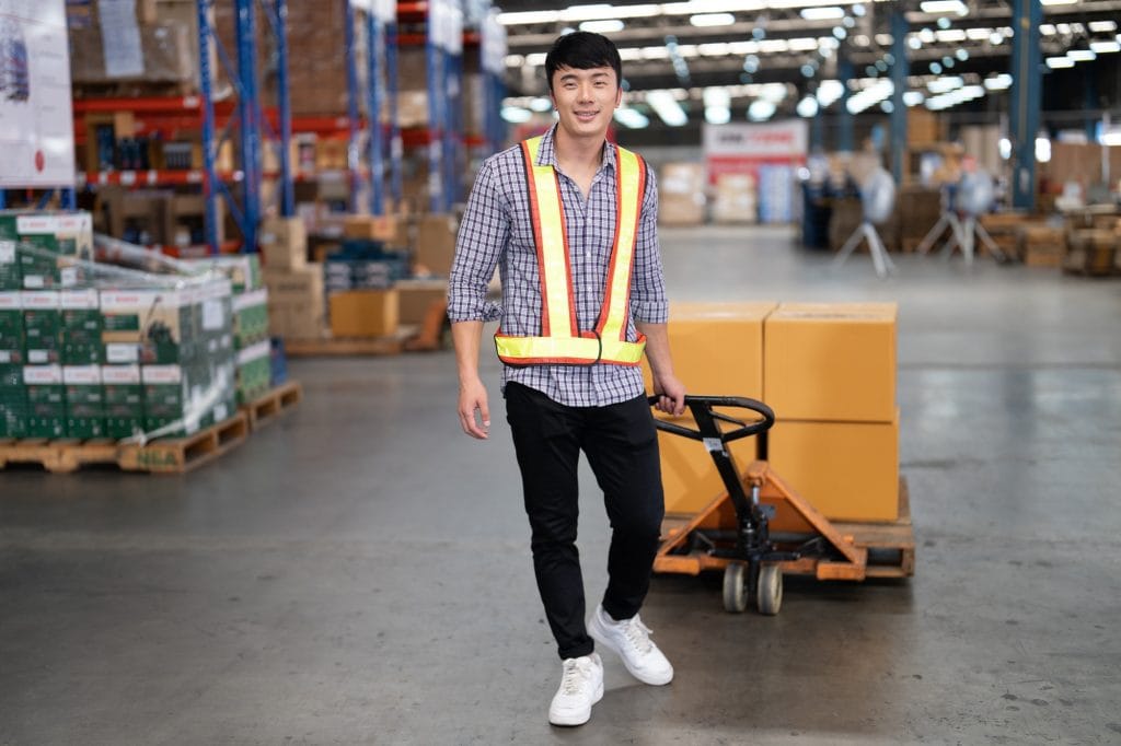 Warehouse worker pulling manual hand pallet lift